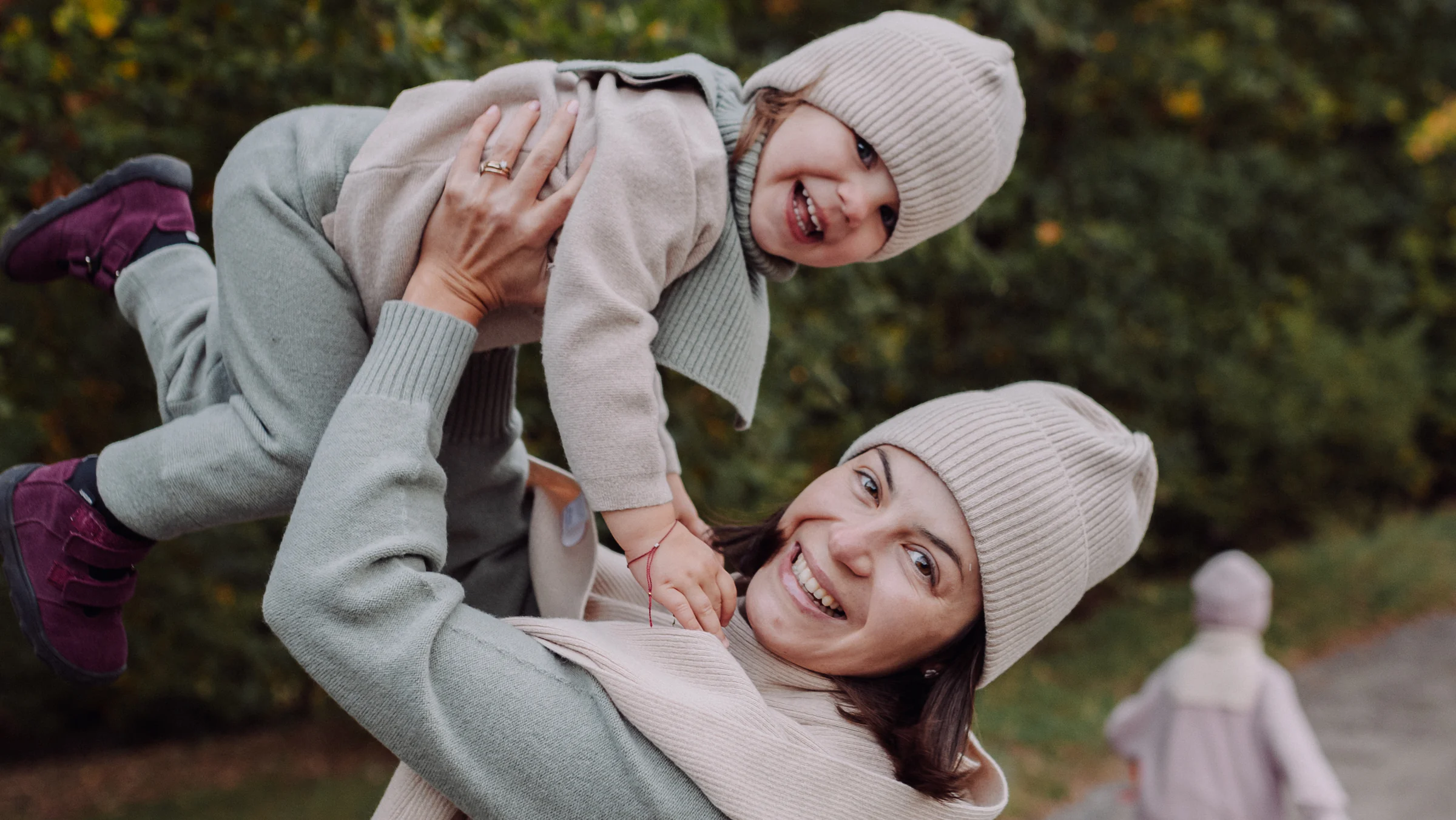 Roześmiana mama z dzieckiem w czapkach i swetrach z wełny merino na jesiennym spacerze